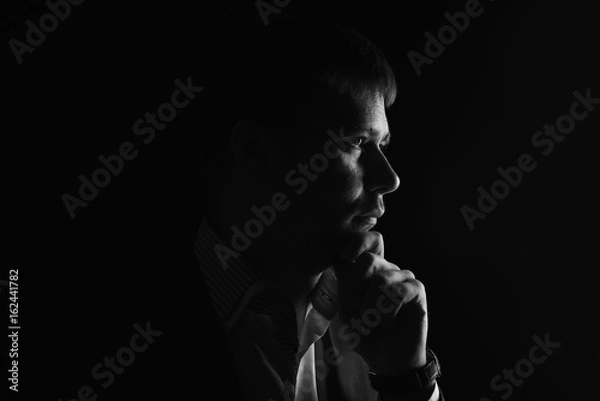 Obraz Man low key high-contrast profile portrait in backlight with a serious look on his face