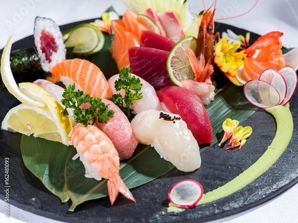 Obraz Mix of sushi and sashimi on a black dish