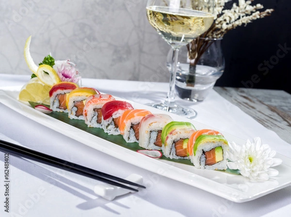 Obraz Rainbow sushi roll with salmon and avocado, complete with a glass of white wine
