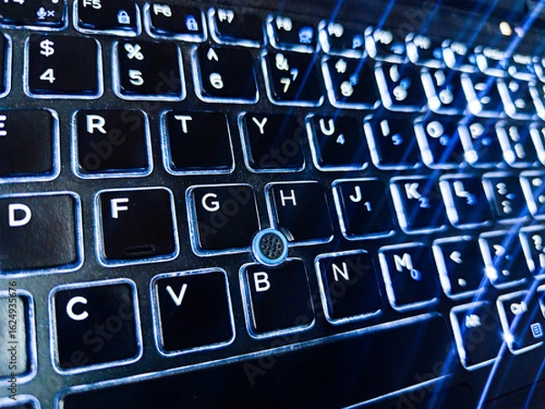 Fototapeta Backlit laptop keyboard with glowing illuminated keys in the dark