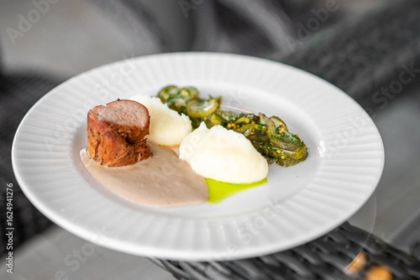 Fototapeta Elegant gourmet dish featuring roasted meat with creamy sauce, mashed potatoes, and sautéed vegetables, artistically plated on a white plate.