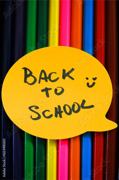 Fototapeta Texture of colored pencils vertically, and a label or emoji above it written back to school and a drawn a happy face near it.