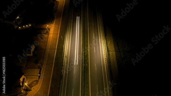 Fototapeta Aerial Long Exposure of Single Car Light Trail on Empty Highway at Night.