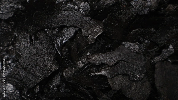 Fototapeta Dark textured black coal background with rough surface details, perfect for use in design, food styling, or artistic projects. Close up, top view