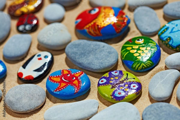 Fototapeta Rounded colorful stones pebbles shingle with pictures painted on them
