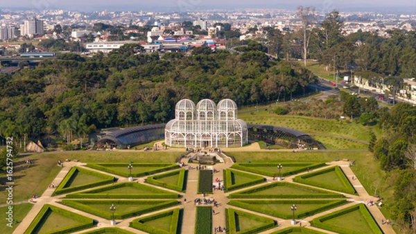 Obraz Front aerial shot of Curitiba’s iconic greenhouse and formal gardens with surrounding forest and distant city.