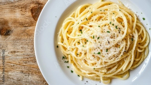 Fototapeta A plate of spaghetti topped with grated cheese and herbs, served on a wooden table, showcasing a delicious Italian dish.
