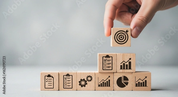 Fototapeta Person placing a target icon block on a stack of blocks with business icons