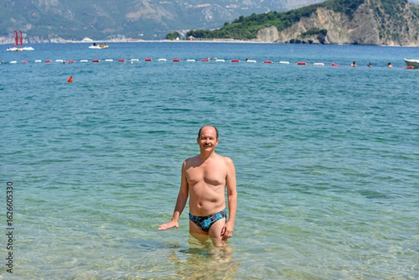 Fototapeta Man is standing  in water of Mogren beach, Budva, Montenegro.