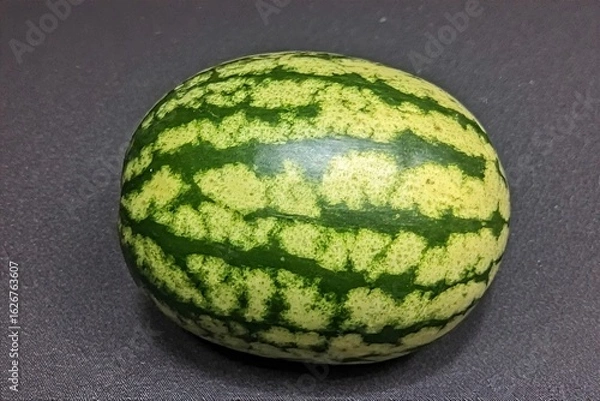 Fototapeta Whole and slice of ripe watermelon, heap of watermelon slices as background