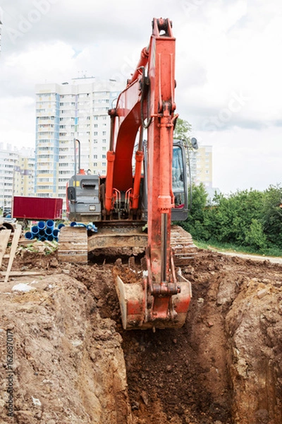 Fototapeta Excavator working on a construction site. Digging the trench for the pipeline.