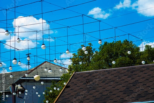 Fototapeta Flashlights and roofs in the town in summer