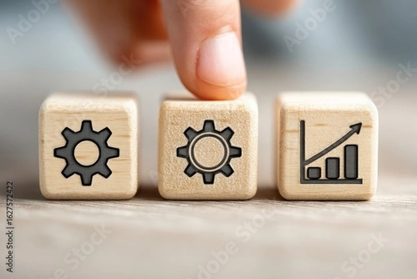 Obraz Hand placing a finger on a wooden block with a gear icon, alongside blocks with gears and growth chart