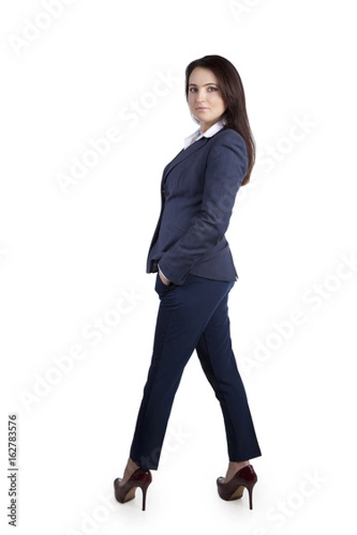 Fototapeta Elegant and confident office worker woman in a business suit, standing in heels. In the studio on white background