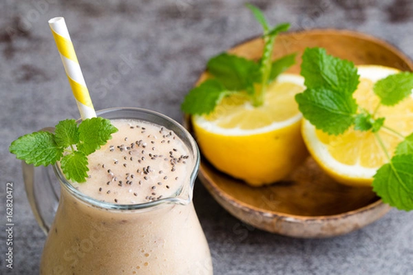 Fototapeta Banana and lemon smoothie, on the grey  background.
