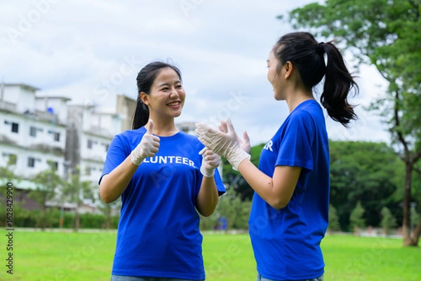 Fototapeta Volunteers showing thumbs up and wearing gloves in a park