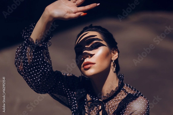 Fototapeta Woman's Face with Shadow Traces from Her Hand, Dramatic Play of Light and Shadow