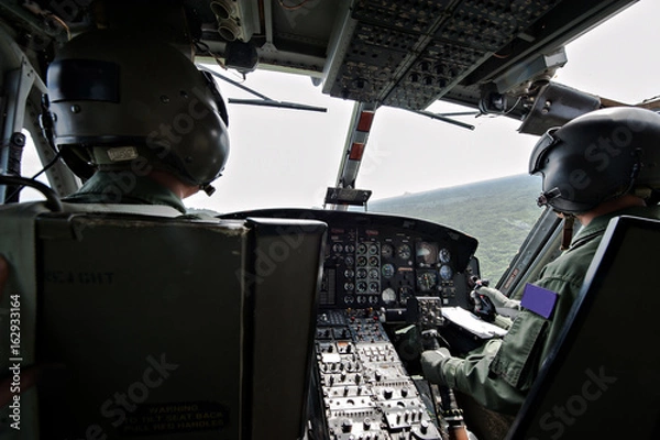 Fototapeta Wnętrze kokpitu detale helikoptera wojskowego z pilotem i pilotem na pokładzie podczas lotu nad rzeką. Pilot przygotowuje się do lądowania.
