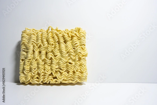 Obraz A close-up shot of a block of uncooked instant noodles, showing its distinctive wavy texture and shape, ready to be prepared.