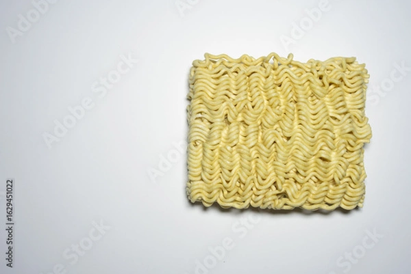 Obraz A close-up shot of a block of uncooked instant noodles, showing its distinctive wavy texture and shape, ready to be prepared.