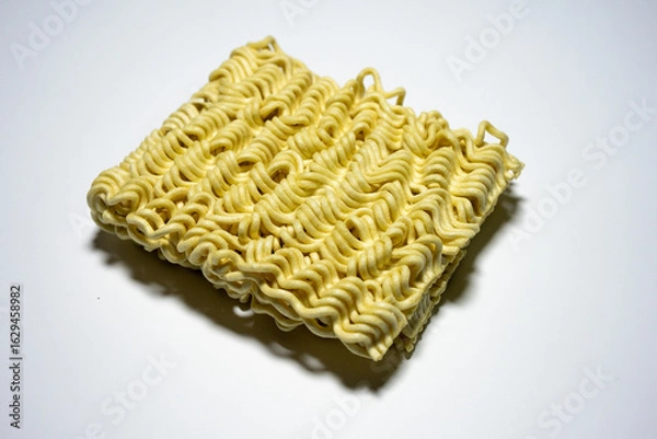 Obraz A close-up shot of a block of uncooked instant noodles, showing its distinctive wavy texture and shape, ready to be prepared.