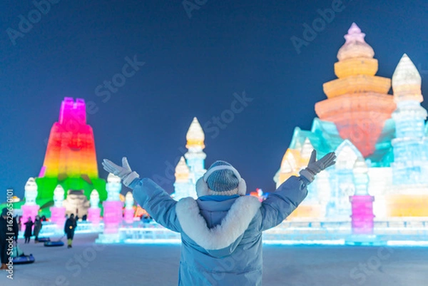 Fototapeta Young happy female tourist enjoying at ice and snow world festival at night in Harbin, China