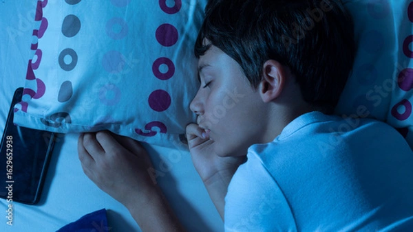 Obraz Child sleeping with smartphone next to pillow at night