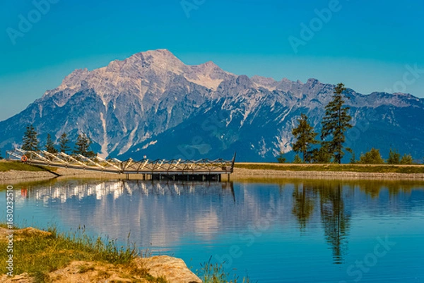 Fototapeta Alpine summer view with reflections and the Leoganger Steinberge mountains in the background at Lake Prinzensee, Mount Natrun, Maria Alm am Steinernen Meer, Salzburg, Austria