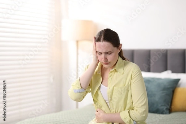 Fototapeta Young woman suffering from headache at home, space for text