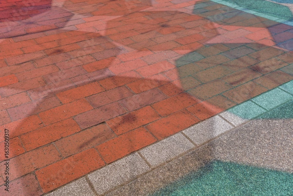 Obraz 夏の晴れた日に、地面に映る色とりどりの傘の影