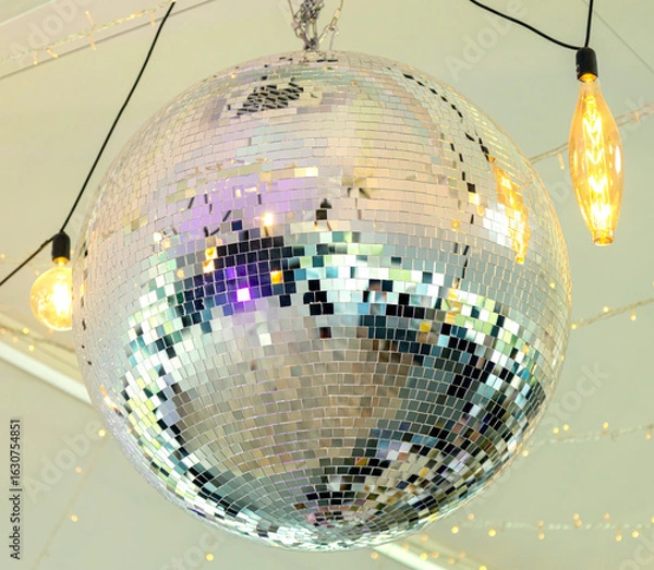 Fototapeta Disco ball in the light of the party. The magic of the mirror ball.