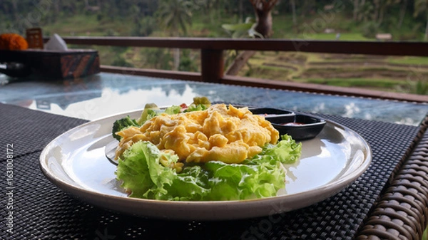 Fototapeta Freshly cooked golden yellow scrambled eggs served hot on a plate with vegetables and condiments. Perfect for breakfast, culinary blogs, food styling, and recipe illustrations. Close up