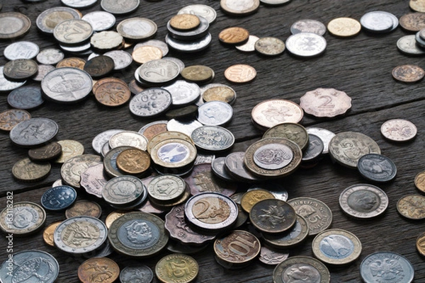 Fototapeta A pile of coins from different countries on a wooden table