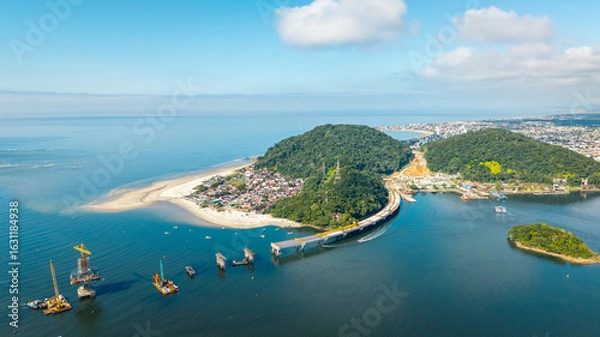 Obraz Wide aerial view of Guaratuba-Matinhos bridge construction with sandy beaches, forested hills and Guaratuba city in the background.