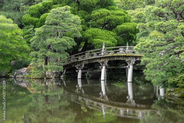 Fototapeta Historic stone bridge crosses a pond in a magnificent Japanese garden (Gonaitei). Kyoto Imperial palace, Japan.