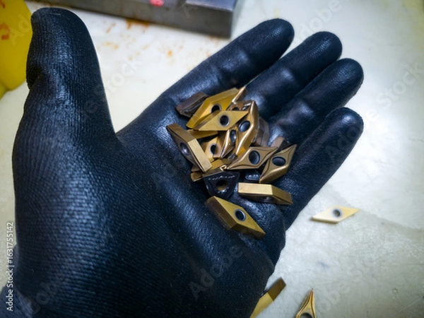 Fototapeta Collection of precision cutting tools in a hand wearing a protective glove in a workshop environment
