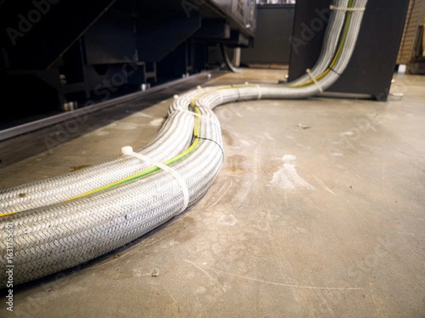 Fototapeta Cables running along the floor in an industrial setting during a maintenance routine