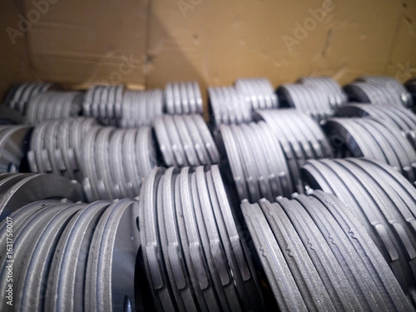 Fototapeta Steel components stacked neatly in a cardboard box at an industrial workshop in the morning light