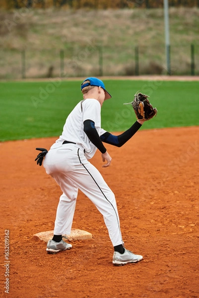 Fototapeta Dynamic teenage boy showcasing skills on the baseball field during practice