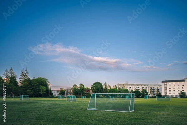 Obraz Peaceful Urban Soccer Field with Multiple Goals under a Vast Blue Sky and Distant Residential Buildings