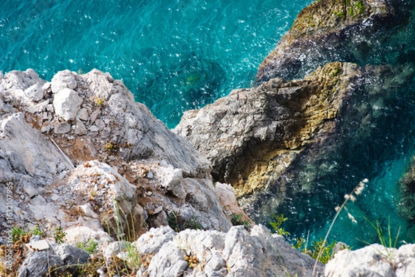 Fototapeta Stunning view of Calella de Palafrugell's pristine coastline featuring traditional whitewashed Mediterranean architecture, crystal-clear turquoise waters, and dramatic rocky outcrops along Costa Brava