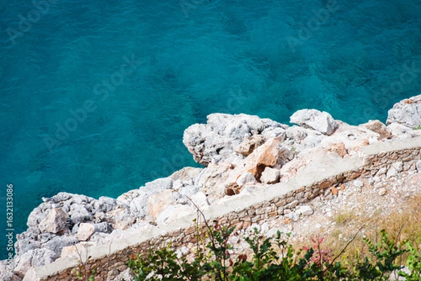Fototapeta Stunning view of Calella de Palafrugell's pristine coastline featuring traditional whitewashed Mediterranean architecture, crystal-clear turquoise waters, and dramatic rocky outcrops along Costa Brava