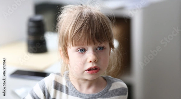 Fototapeta Young child with striking blue eyes engages in playful conversation in a cozy home environment during midday hours