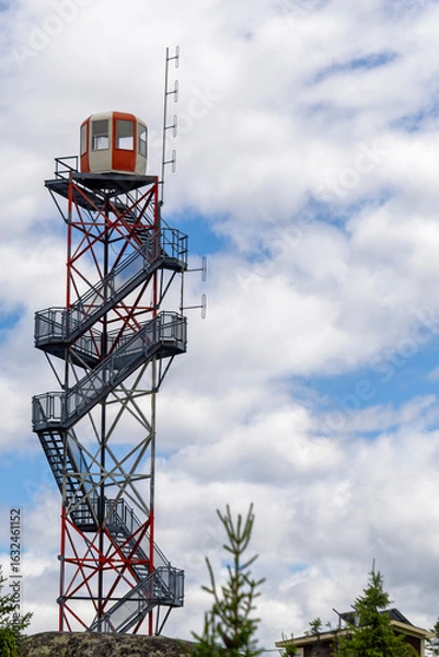 Fototapeta A fire tower with clouds and blue sky in the background.