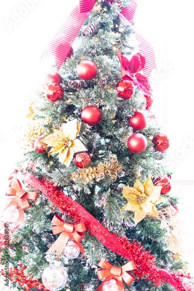 Fototapeta A brightly lit background featuring a Christmas tree that has been decorated red and gold. Their are several round ornaments as well as large flower ornaments and garland or tinsel. 