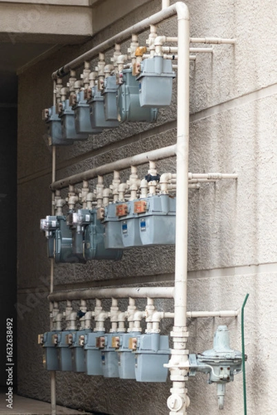 Fototapeta A dim lit corridor with several utility meters bunched together. The utility meters are part of an apartment complex.