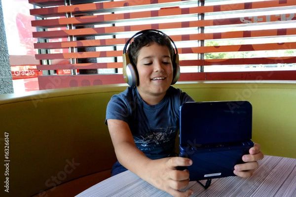 Obraz El niño con Auriculares esta jugando con juegos electronicos