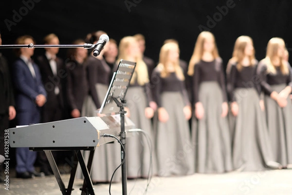 Fototapeta Microphone and music stand in front of electric pianos on the stage of the theater