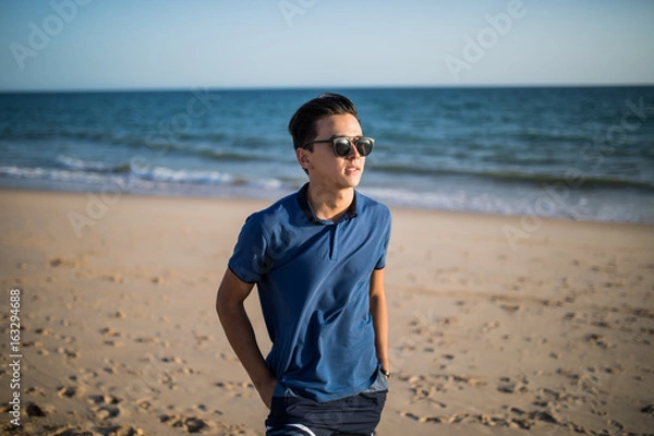 Fototapeta Relaxing and smiling asian young man on the beach