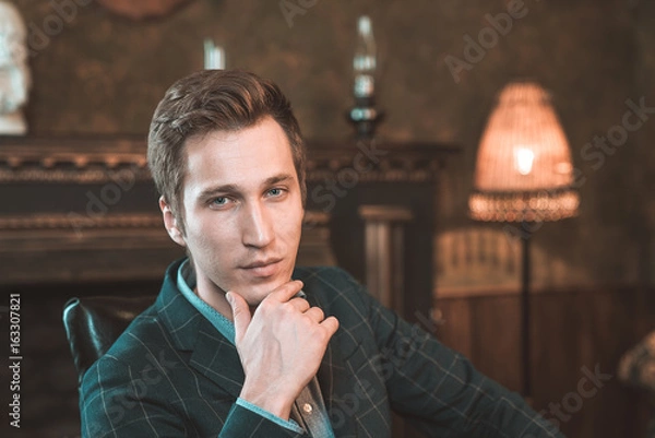 Obraz Portrait of a business man who sits by the fireplace with a thoughtful look...